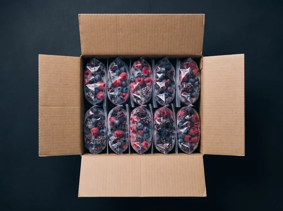Caja de cartón abierta con diez bolsas de 1 kg de berries congelados